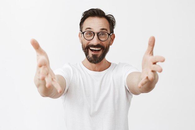 Hombre maduro barbudo sorprendido y feliz con gafas posando