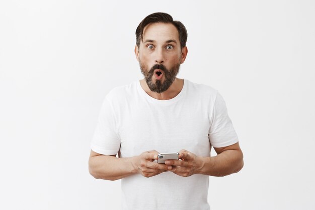 Hombre maduro guapo con barba posando con su teléfono