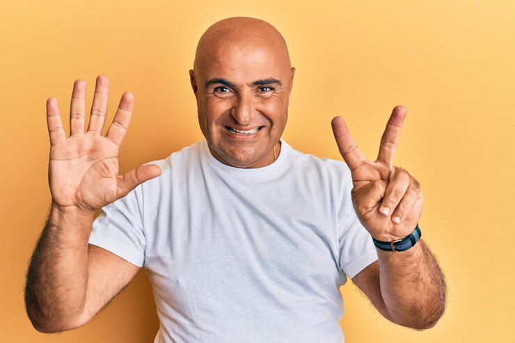 Foto gratuito hombre maduro de oriente medio con camiseta blanca informal que aparece y señala con los dedos número siete mientras sonríe confiado y feliz.