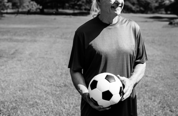 Hombre maduro sosteniendo un balón de fútbol