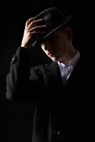 Foto gratuita hombre mafioso guapo tocar el sombrero en la oscuridad