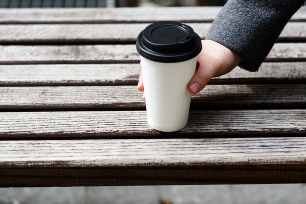 Hombre con manga gris toma papel taza de café