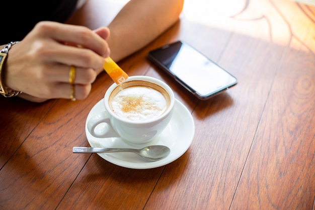 Hombre mano poniendo azúcar en la taza de café