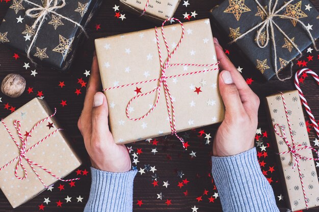 Hombre manos sosteniendo la caja de regalo de vacaciones de Navidad en mesa festiva decorada