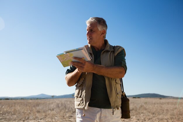 Hombre con mapa mirando a otro lado en el paisaje