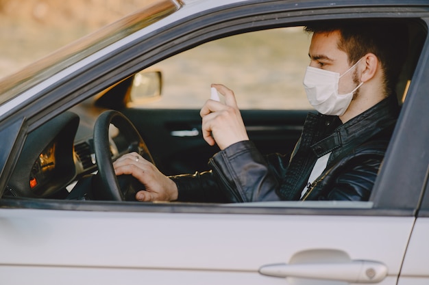 El hombre en una máscara desinfecta el auto