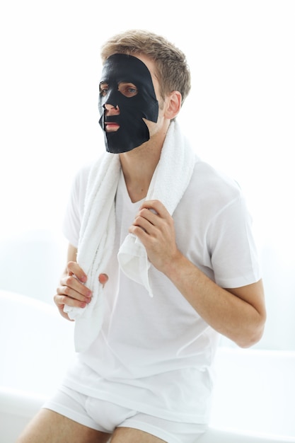 Hombre con máscara facial negra, carbón purificador de la piel. Concepto de belleza