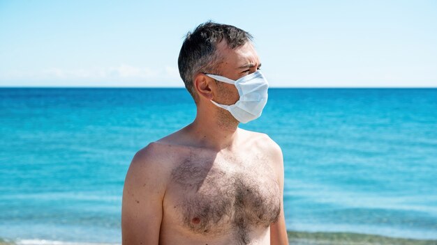 Un hombre con máscara médica blanca en el mar.