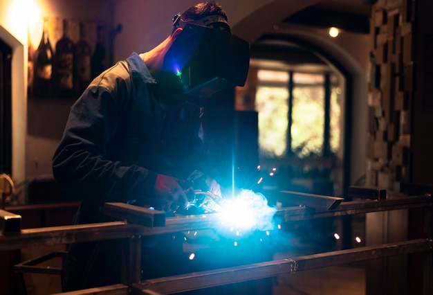 Hombre con máscara de soldadura de metal en el atelier