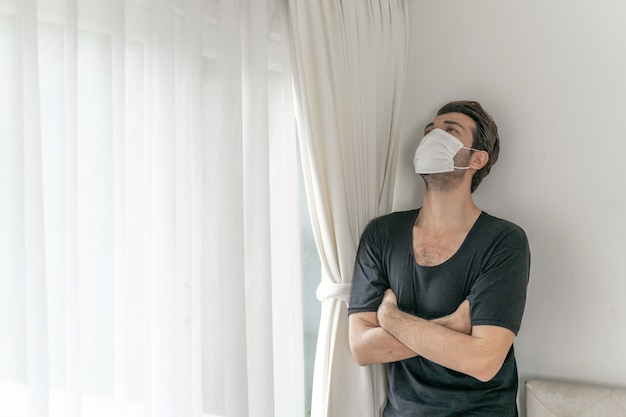 Foto gratuita hombre con mascarilla para proteger la sensación de malestar dolor de cabeza y tos debido al coronavirus covid-19 en la sala de cuarentena