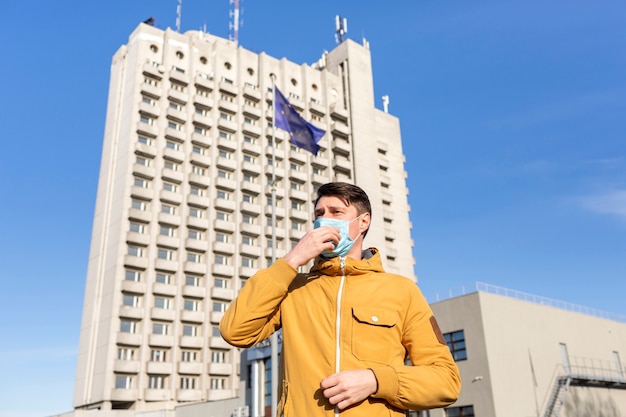 Foto gratuita hombre con mascarilla quirúrgica al aire libre