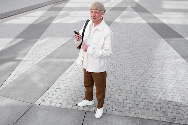 Hombre mayor al aire libre en la ciudad con smartphone con auriculares