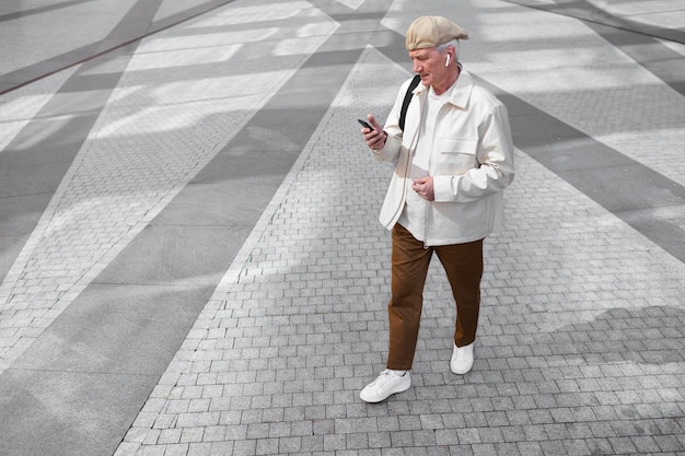 Foto gratuita hombre mayor al aire libre en la ciudad con smartphone con auriculares