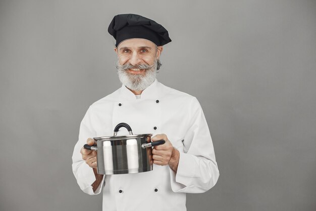 Hombre mayor con bandeja de metal. Chef con sombrero negro.