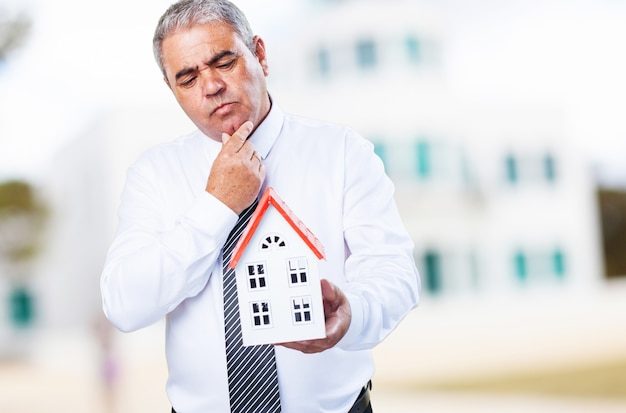 Hombre mayor con una casa en sus manos