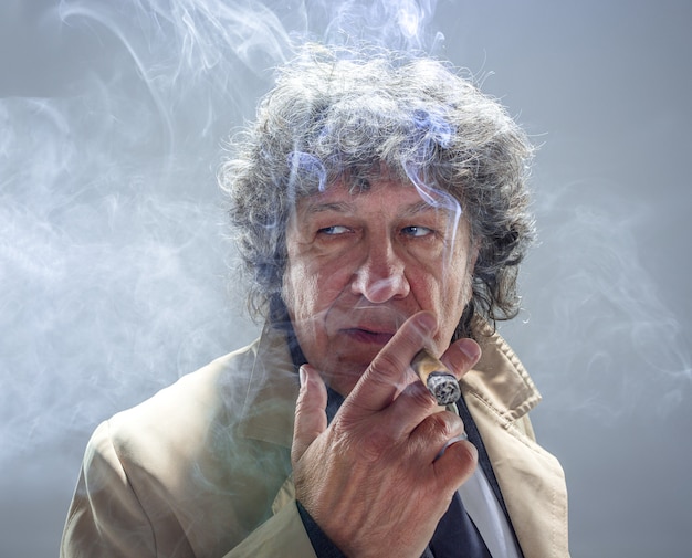 Foto gratuita el hombre mayor con cigarro como detective o jefe de la mafia