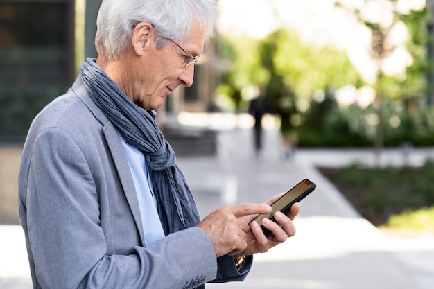 Foto gratuita hombre mayor en la ciudad con smartphone