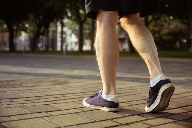 Hombre mayor como corredor en la calle de la ciudad. Primer plano de piernas en zapatillas