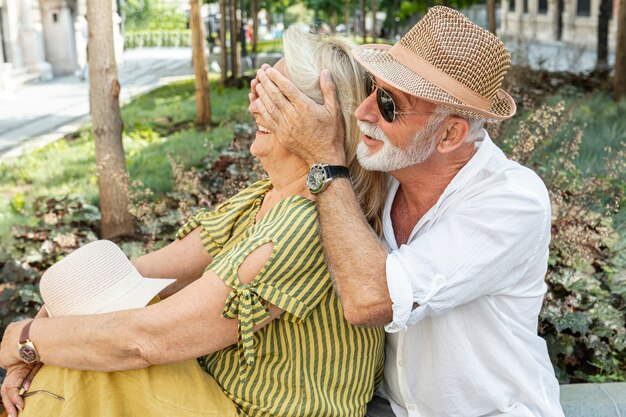 Hombre mayor cubriendo los ojos de la mujer con sus palmas