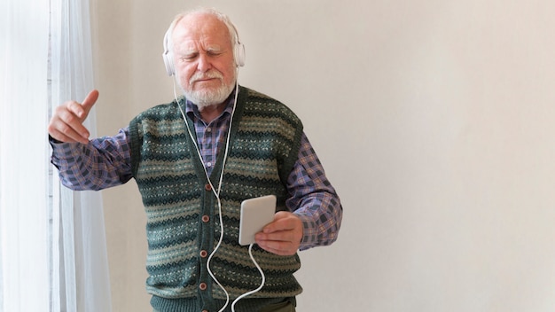 Hombre mayor escuchando música con espacio de copia