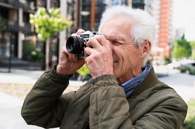 Hombre mayor con estilo en la ciudad con cámara para tomar fotos