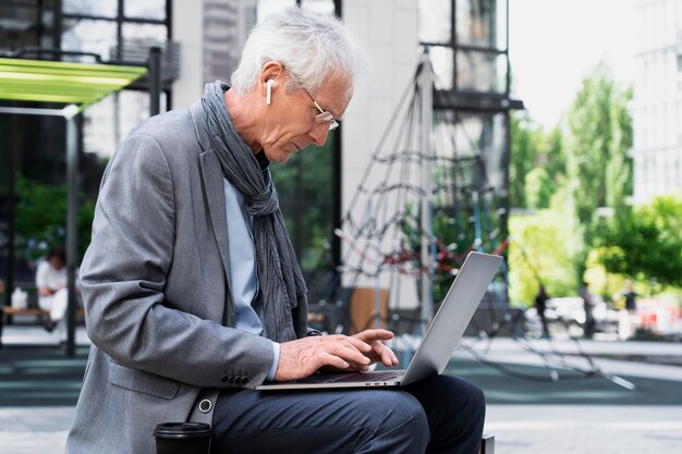 Hombre mayor con estilo en la ciudad usando laptop