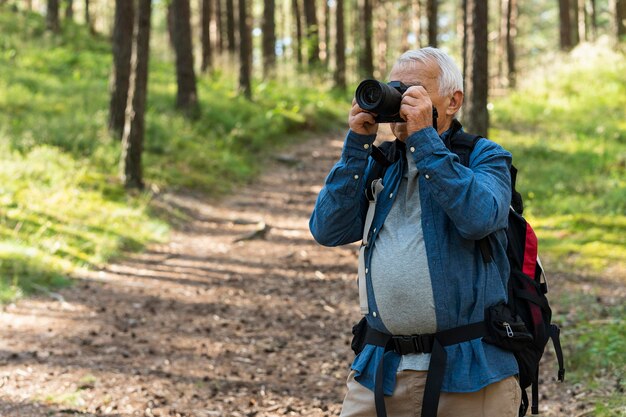 Hombre mayor explorando la naturaleza con cámara