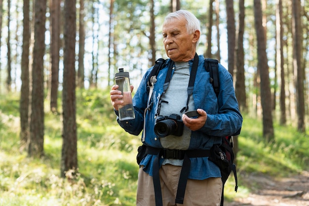 Hombre mayor hidratado mientras explora la naturaleza