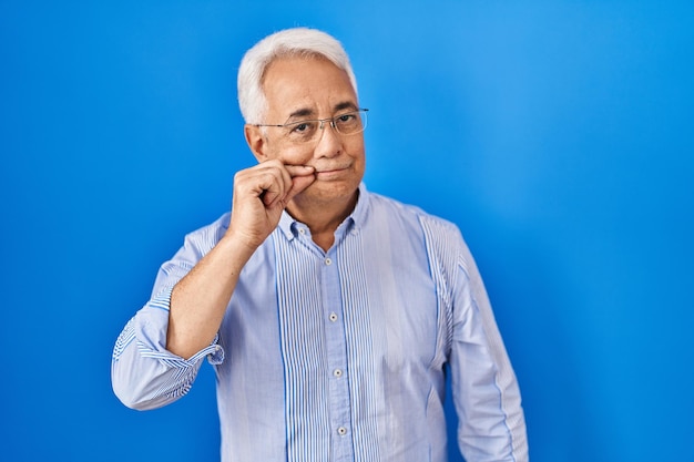 Foto gratuita hombre mayor hispano con anteojos boca y labios cerrados como zip con los dedos. secreto y silencioso, tabú hablando