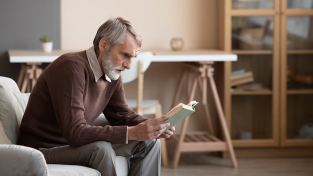 Hombre mayor leyendo un libro en casa