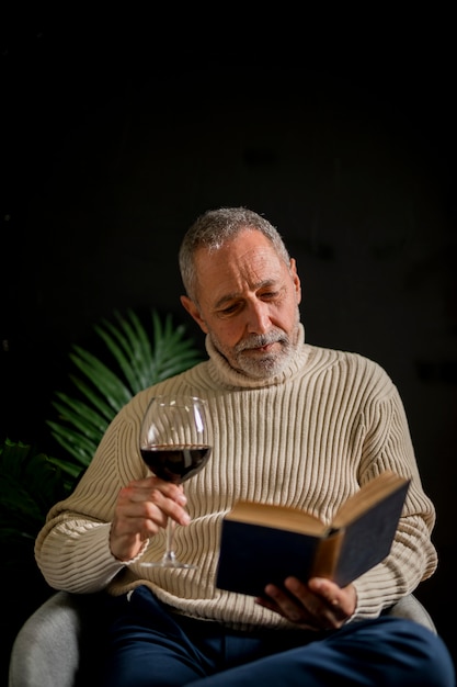 Hombre mayor con libro de lectura de vino