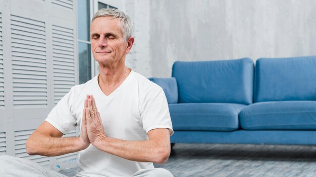 Hombre mayor meditando con las manos orando