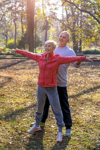 Hombre mayor y una mujer haciendo ejercicio juntos en el parque en otoño