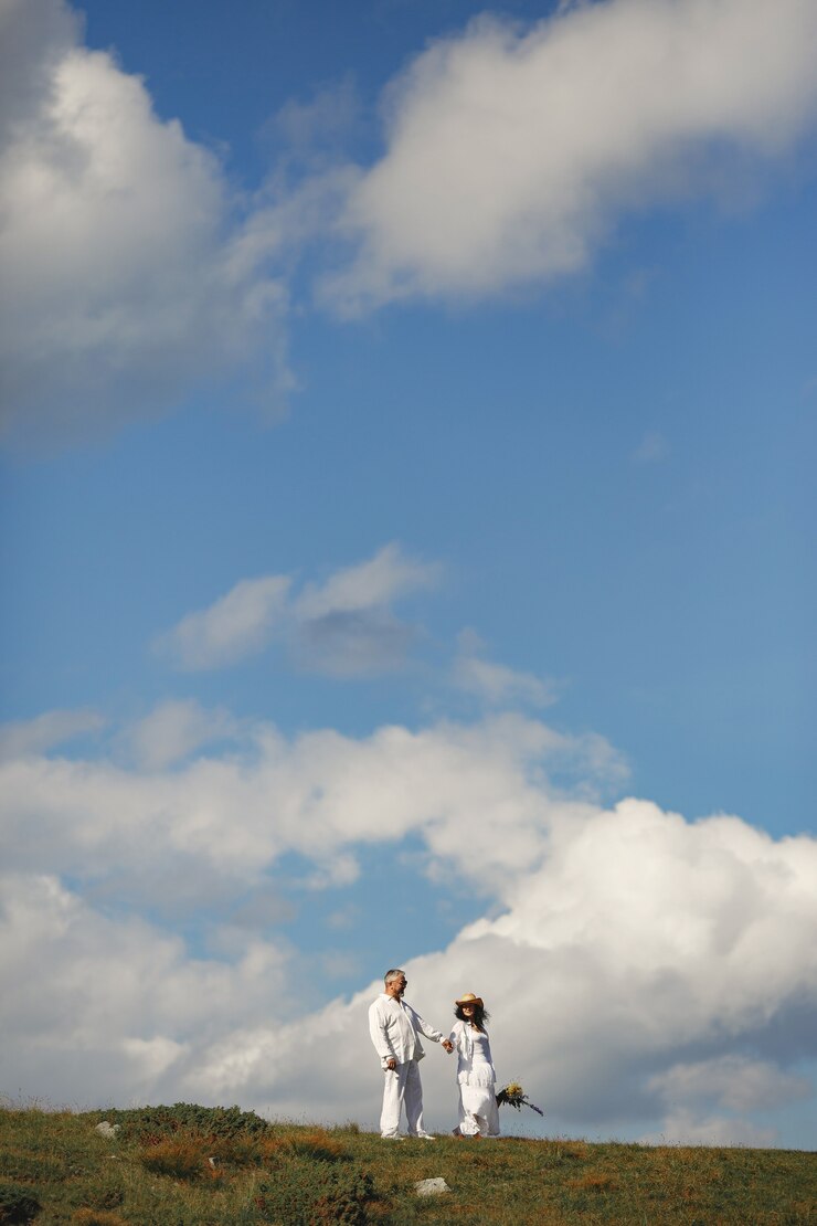 Foto gratuito hombre mayor y mujer en las montañas. mujer con canasta de flores. hombre con camisa blanca.
