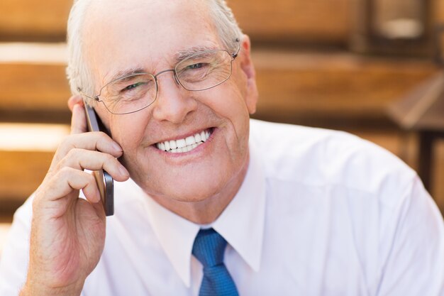 Hombre mayor de negocios hablando por teléfono y sonriendo