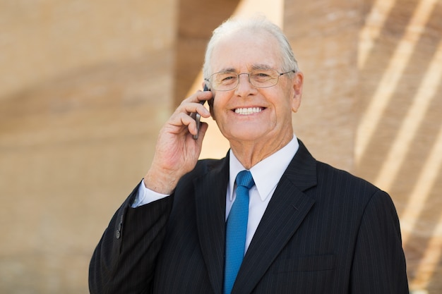 Hombre mayor de negocios hablando por teléfono y sonriendo