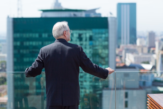 Hombre mayor de negocios mirando por una terraza