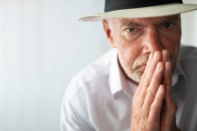 hombre mayor, posar, en, camisa blanca, y, sombrero