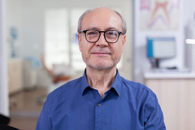 Foto gratuita hombre mayor que mira la cámara en el consultorio dental wainting consulta hombre mayor sonriendo en la cámara web s ...