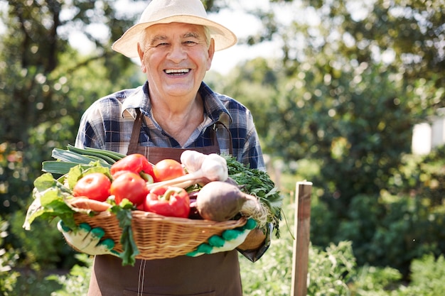 Hombre mayor que trabaja en el campo con una caja de verduras