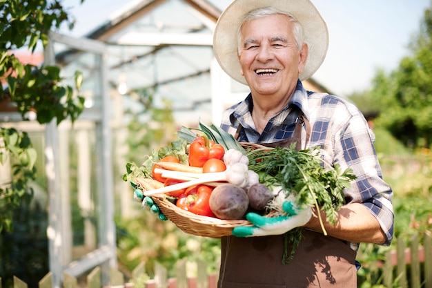 Hombre mayor que trabaja en el campo con una caja de verduras