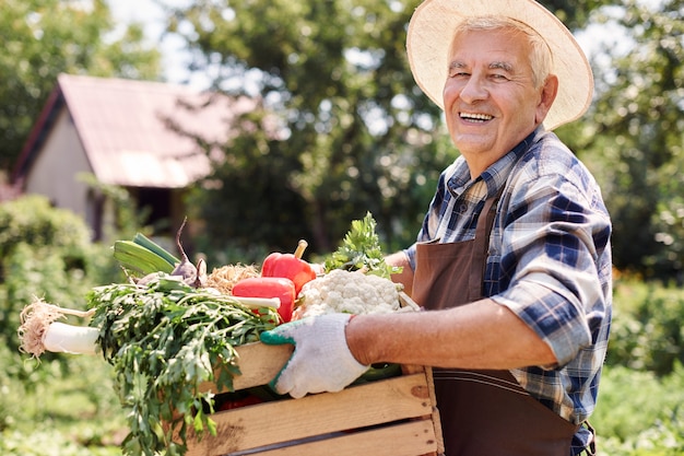 Hombre mayor que trabaja en el campo con flores