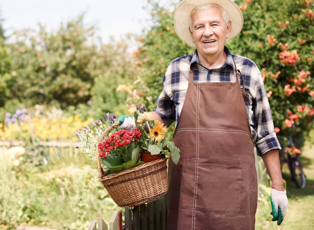 Hombre mayor que trabaja en el campo con flores