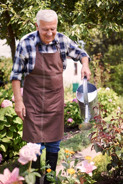 Foto gratuita hombre mayor que trabaja en el campo con flores