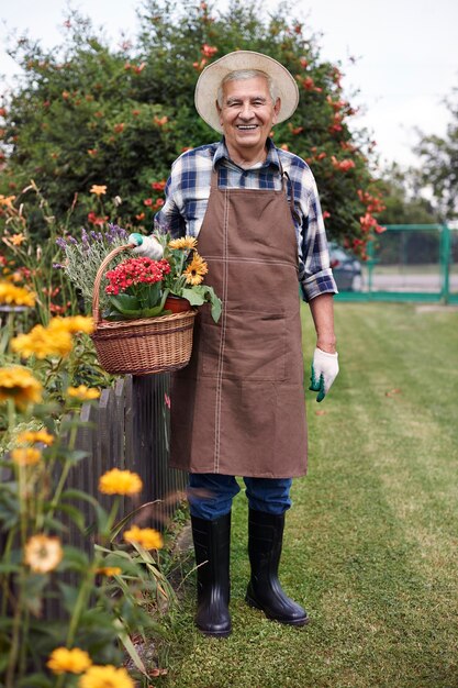 Hombre mayor que trabaja en el campo con flores