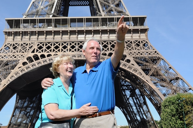 Hombre mayor señalando algo a su esposa junto a la torre eiffel