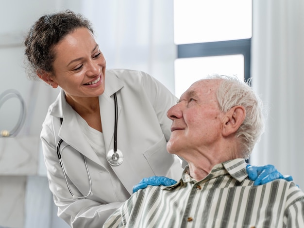 Foto gratuita hombre mayor sentado en silla de ruedas junto a un médico