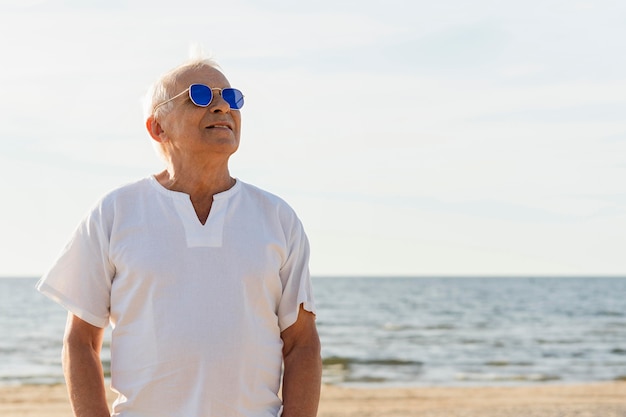 Hombre mayor sonriente con gafas de sol disfrutando de su tiempo en la playa