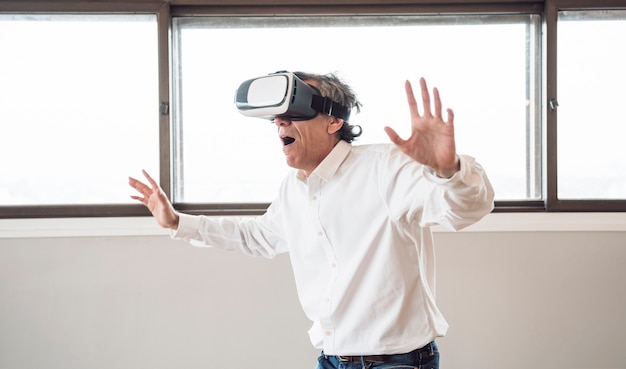Hombre mayor sorprendido usando un casco de realidad virtual en la habitación
