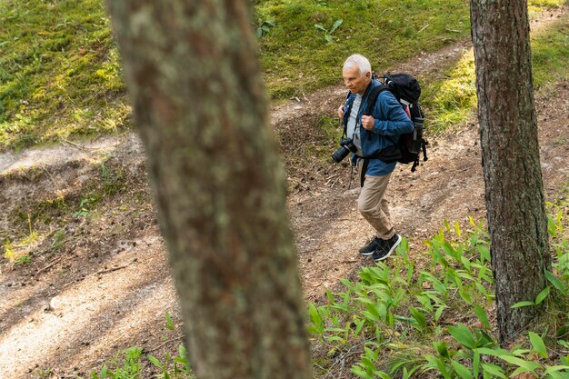 Hombre mayor viajando en la naturaleza con mochila